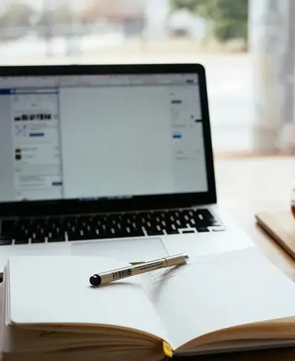 A laptop with a notepad and pen - Core42 News
